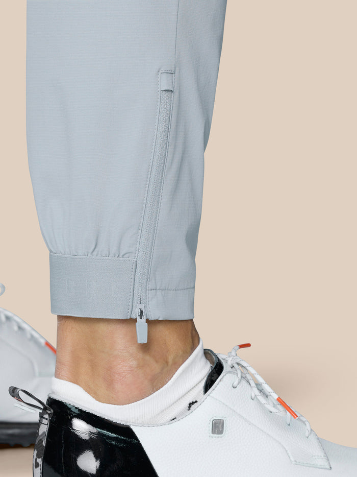 Close up of the pant leg cuff showing ankle zipper and adjustable hem on light grey golf pants