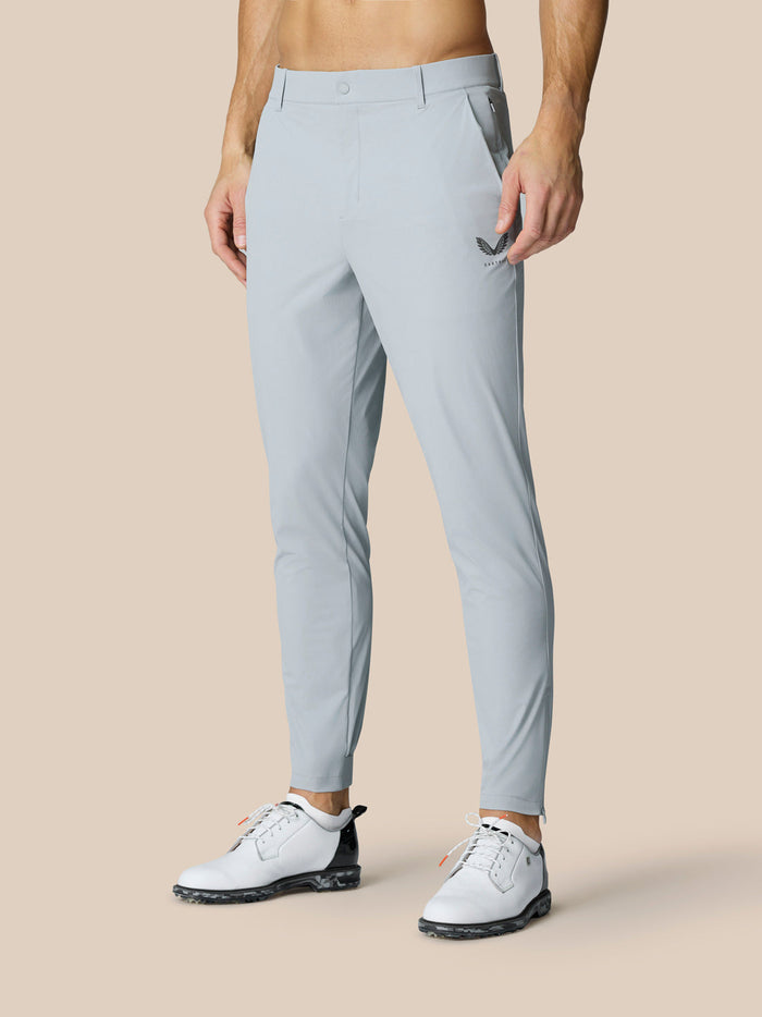 Male model wearing light grey Golf Pinnacle 32 inch pants with open side pockets and Castore logo on thigh