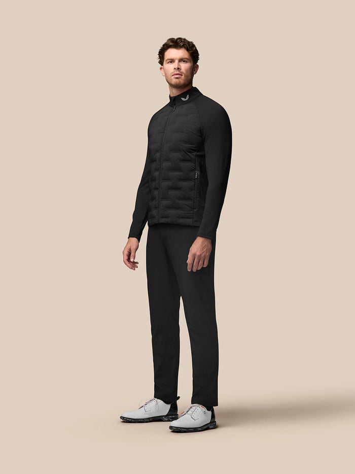 Three-quarter view of a male model in the black Golf Pinnacle jacket showing quilted front panels and stand collar
