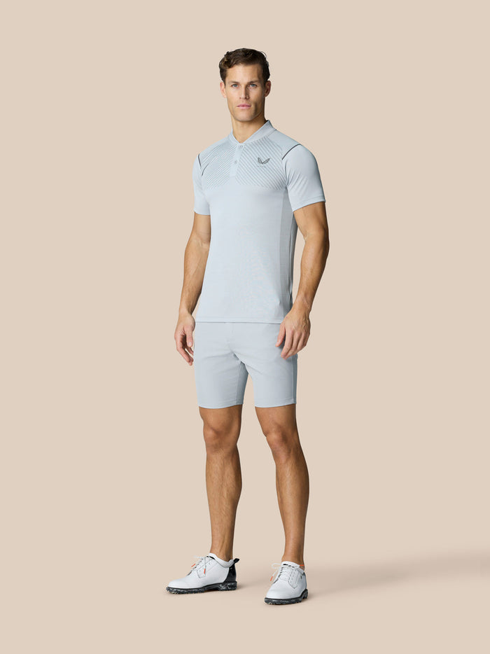 Volledig beeld van een man in een lichtgrijze Pinnacle Golf Polo met bijpassende korte broek.