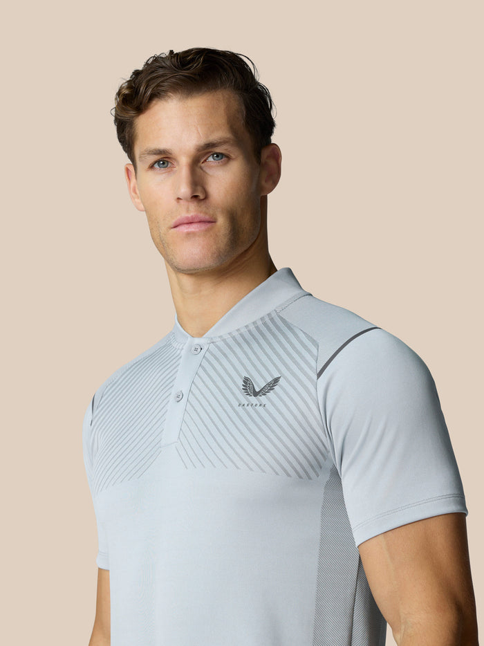 Model draagt een lichtgrijze Pinnacle Golf Polo met diagonale borstpatronen en linker borstlogo.