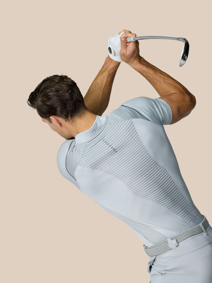 Model in a Pinnacle Golf Polo mid grey during swing side profile highlighting diagonal stripe panels