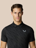 Man wearing black textured golf polo with a subtle dot pattern and Castore logo on the chest