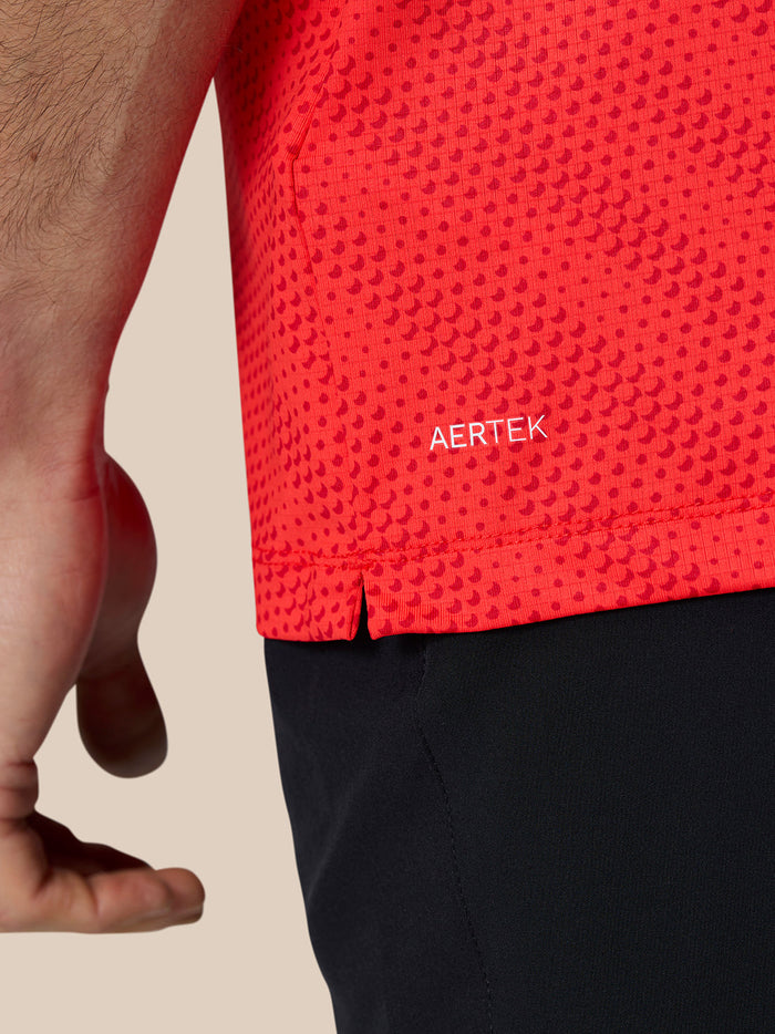 Detail van rode Golf Club Grafische Polo met AERTEK branding aan de zoom en zijsplitten