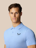 Dichtbijop van een man in de hemelsblauwe Club Golf polo met Castore logo op de borst en een subtiel grafisch patroon aan de onderkant.