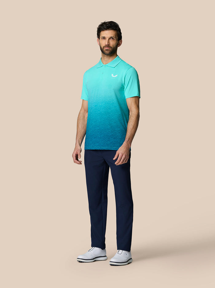 Volledig beeld van een man in Club Grafische Polo Licht Aqua met marineblauwe broek en witte schoenen.