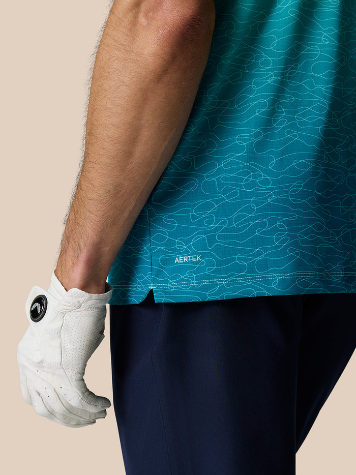 Side view of Club Grafische Polo Licht Aqua showing teal ombre print and the AERTEK label at the hem.