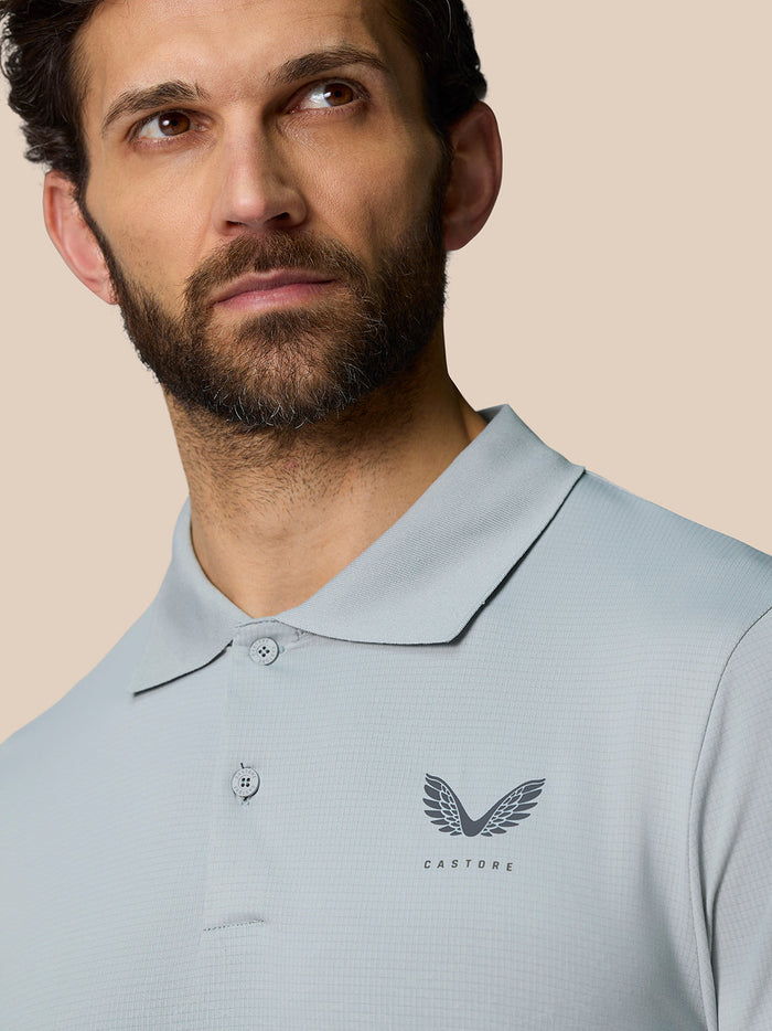 Back view of a man in a pale blue Castore polo with a small winged Castore logo on the left chest