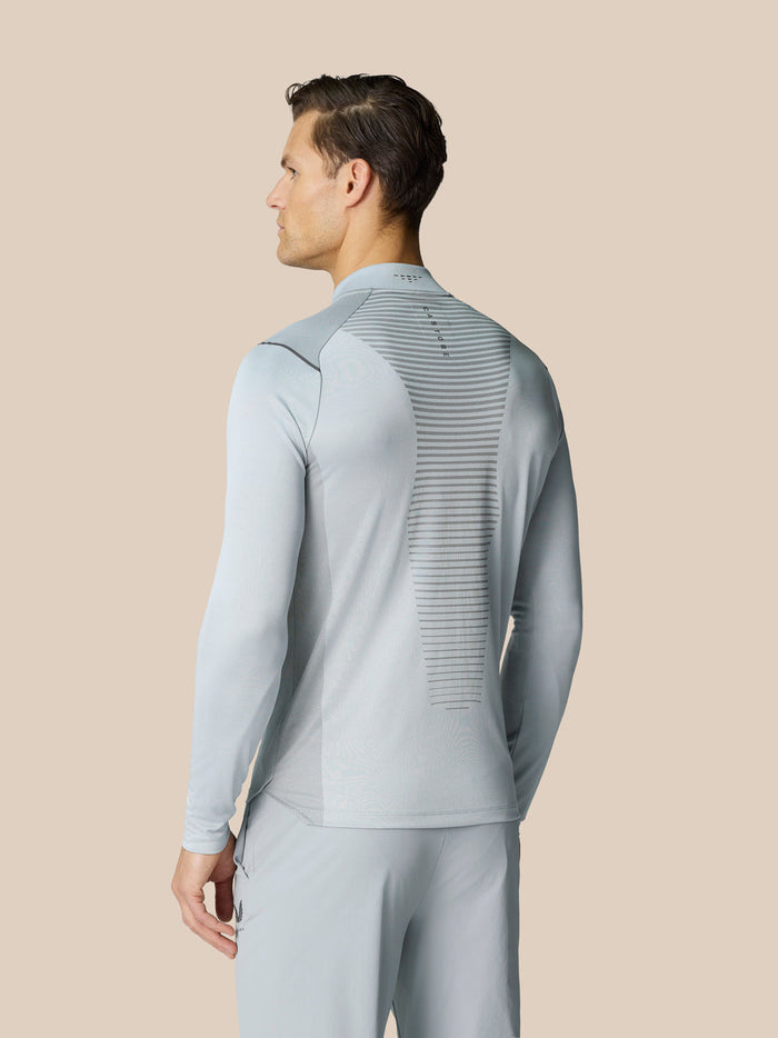 Back view of a man wearing a light gray golf top with LVS ventilation panel and side panels for movement