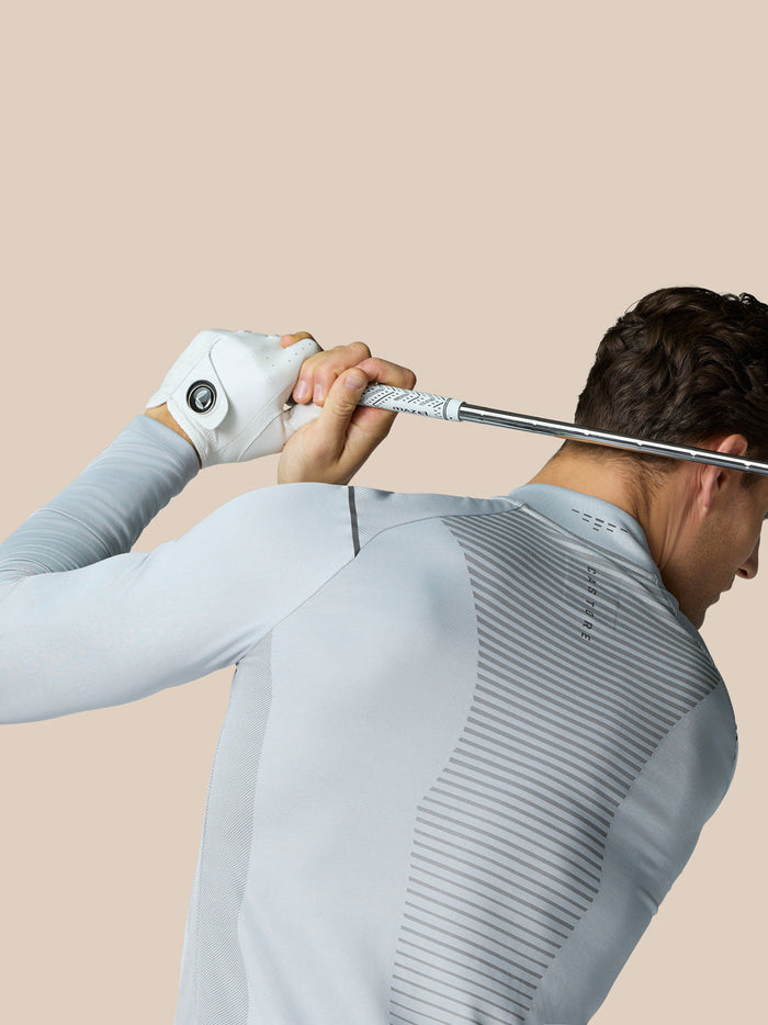 Back view of a golfer in a light gray LVS top with a striped ventilation panel