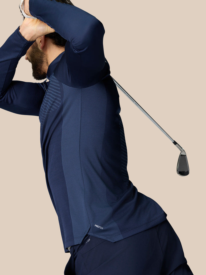 Man in navy golf quarter zip top mid swing showing ventilated panels and ProTek water resistance