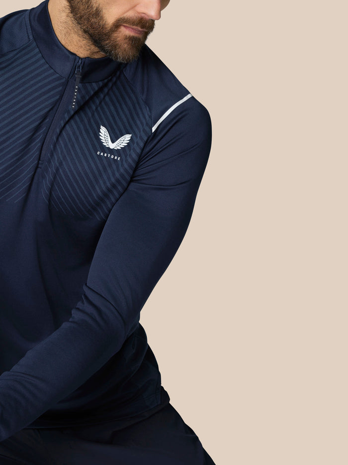 Side view of man in navy Castore golf top with diagonal stripe details and chest logo