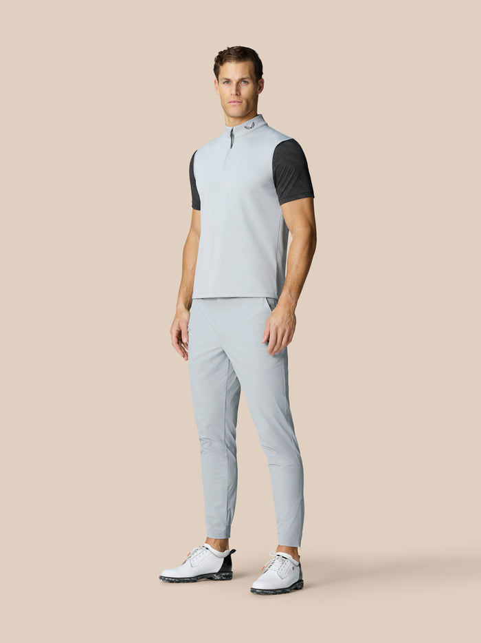 Full body shot of a man in a light grey half zip gilet with matching pants and white golf shoes