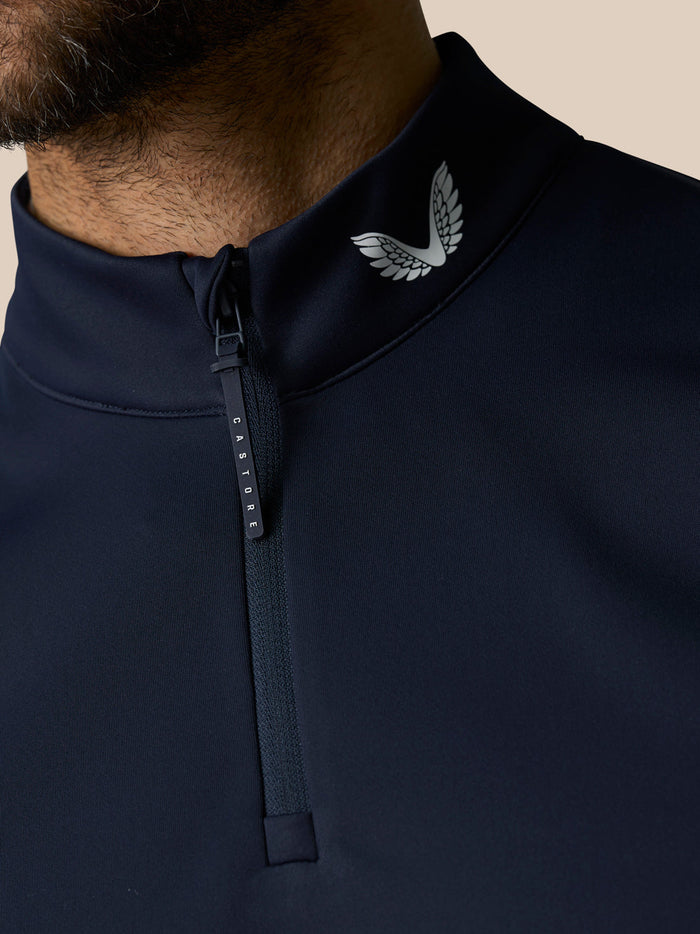 Close-up of navy high collar on the gilet showing a white wing logo and a Castore branded zipper pull.