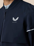 Close up of the navy Pinnacle woven jacket chest showing the white Castore wing logo and front zipper
