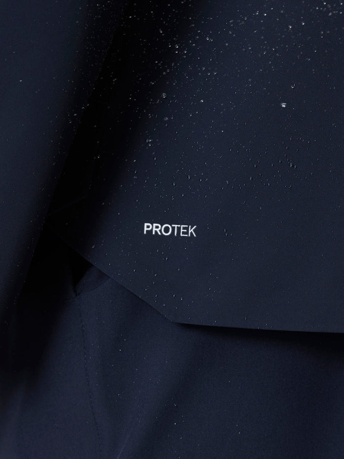Close up of navy jacket fabric with water droplets and the PROTEK branding on the chest area