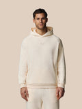 Volledig vooraanzicht van man in oatmeal marl fleece hoodie met Castore logo op de borst en ritzzakken.