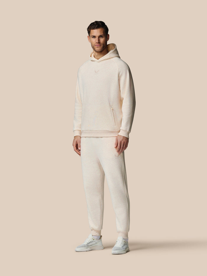 Volledig vooraanzicht van man in oatmeal marl fleece hoodie met wikkelkapuchon en Castore logo op de borst.