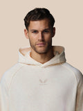 Male model wearing oatmeal fleece hoodie with center chest Castore logo and wraparound hood