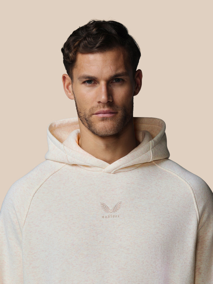 Male model wearing oatmeal fleece hoodie with center chest Castore logo and wraparound hood