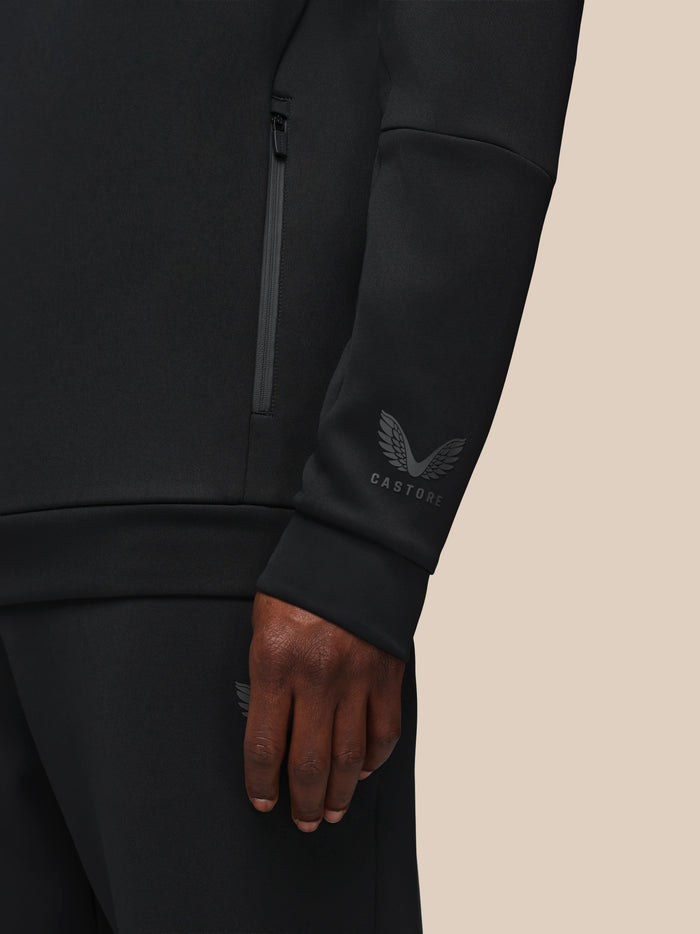 Close up of a black Castore Flex hoodie showing a vertical front zip pocket and the logo on the sleeve.