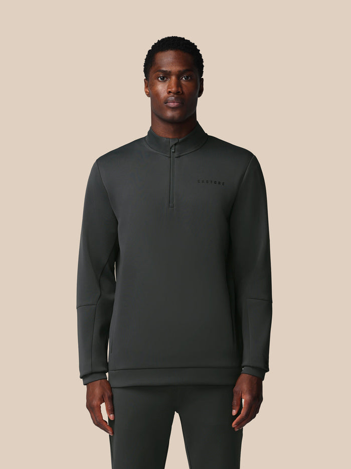 Man draagt donkergrijze Heren Flex lange mouwen kwart‑rits sweatshirt met zijzakken en Castore logo op borst