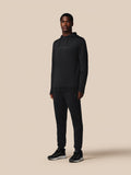 Male model wearing black Flex Joggers and matching hoodie against a beige background