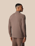 Back view of male model in taupe apex training top with white shoulder piping and Castore branding on the back
