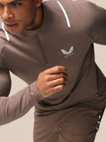 Close up of deep taupe Castore Apex Quarter Zip Top showing reflective shoulder stripe and chest logo