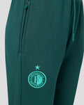 Zijkantdetail van groene junior joggers met een ritsszak en het Feyenoord embleem op het been