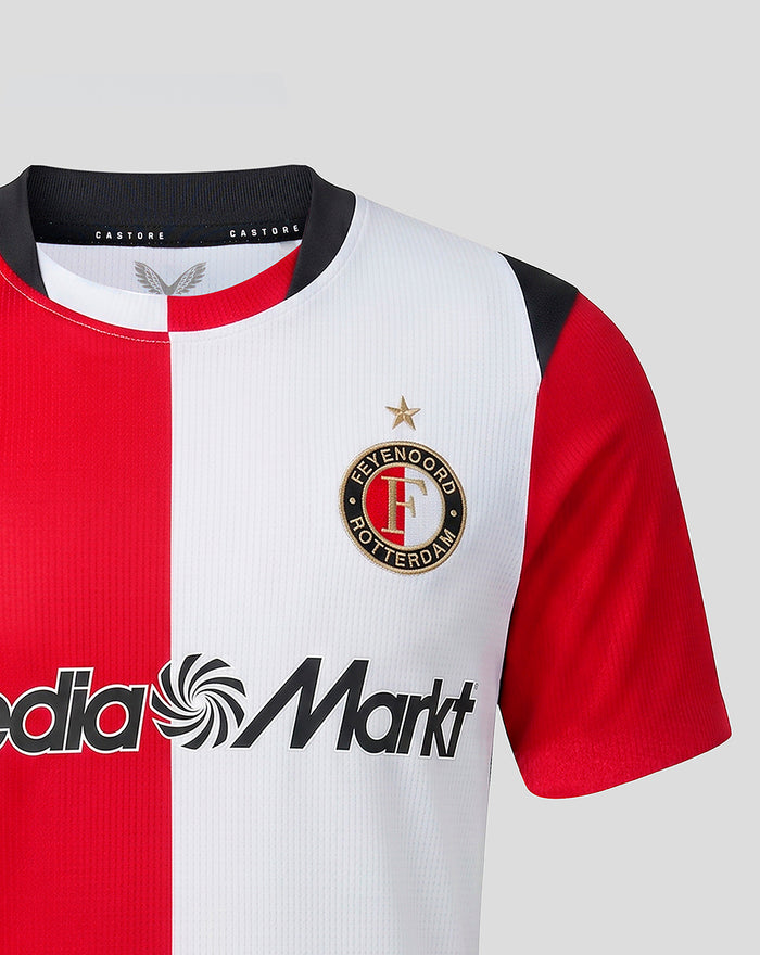 Front view of junior Feyenoord home shirt with red and white split panels, club crest on the left chest, Castore branding at the collar, and Media Markt sponsor across the chest