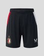 Front view of black Feyenoord junior home shorts with red and white side panels; left leg crest, right leg Castore logo.