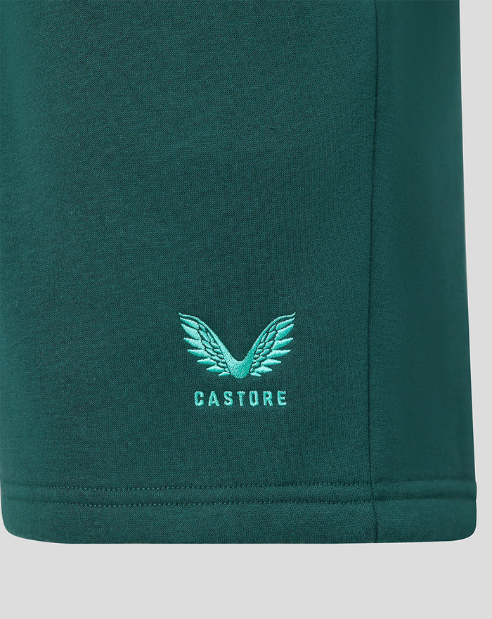 Close up of dark green fleece short with teal winged Castore logo near the hem.