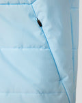 Close-up of light blue padded training gilet fabric showing a zip pocket and stitching details