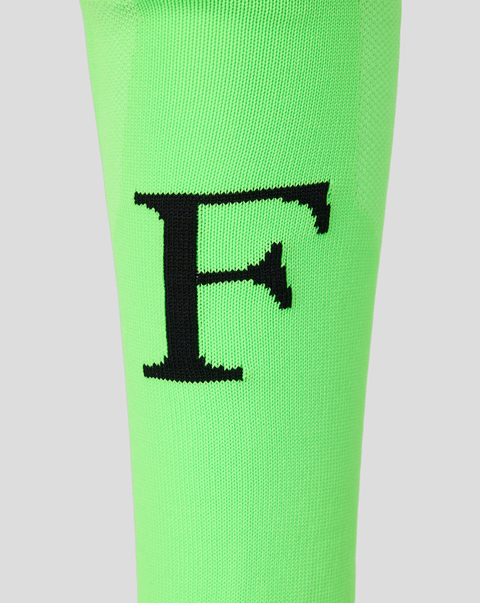 Detail van neon groene Feyenoord keeperskousen met grote zwarte F op het scheenbeen