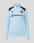 Lichtblauwe dames trainings midlayer met kwartrits en opstaande kraag Castore-logo links Feyenoord badge rechts