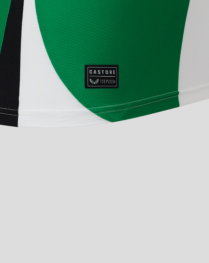 Castore label op groen paneel met witte onderlaag en zichtbare zoomstiksel bij het shirt