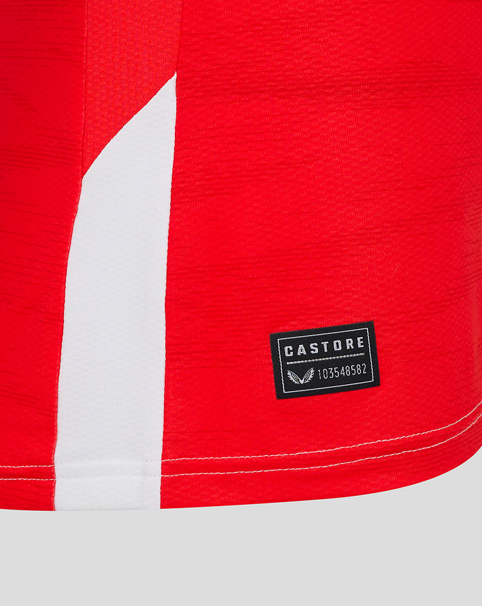 Close up of the jersey hem area showing a red panel white stripe and a Castore label near the edge