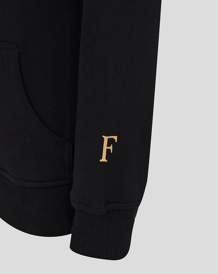 Close-up of black hoodie sleeve with a gold F initial near the cuff