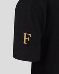 Close-up of a black junior T-shirt sleeve with a gold letter F