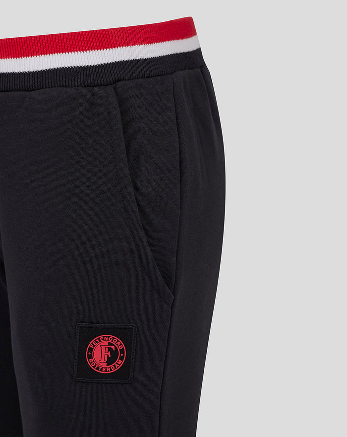 Close up of black junior joggers showing the striped waistband and a red circular Feyenoord patch on the leg