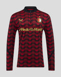 Feyenoord home matchday midlayer top 2025-26 front view featuring red circular pattern with gold Castore logo and MediaMarkt sponsor.
