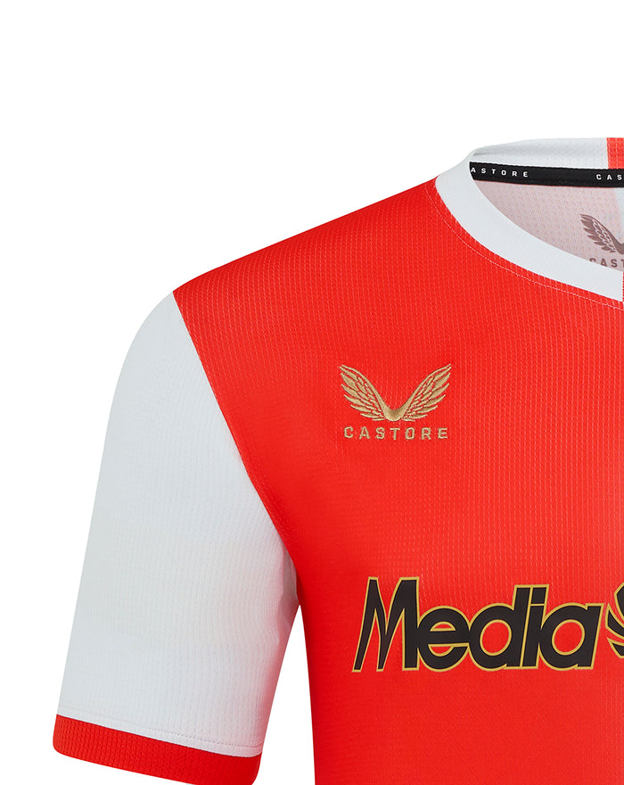Close-up of Feyenoord 2025-2026 home shirt shows gold Castore emblem on red panel and MediaMarkt sponsor across the chest