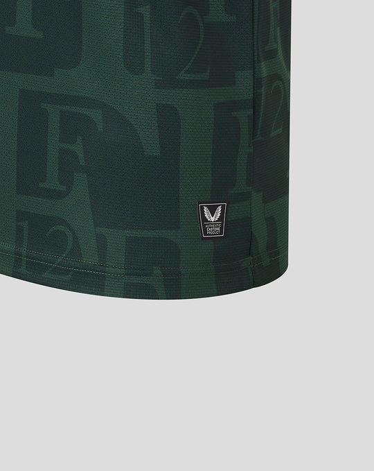 Close-up of dark green Twaalfde shirt fabric with a small black Castore authenticity badge at the hem.