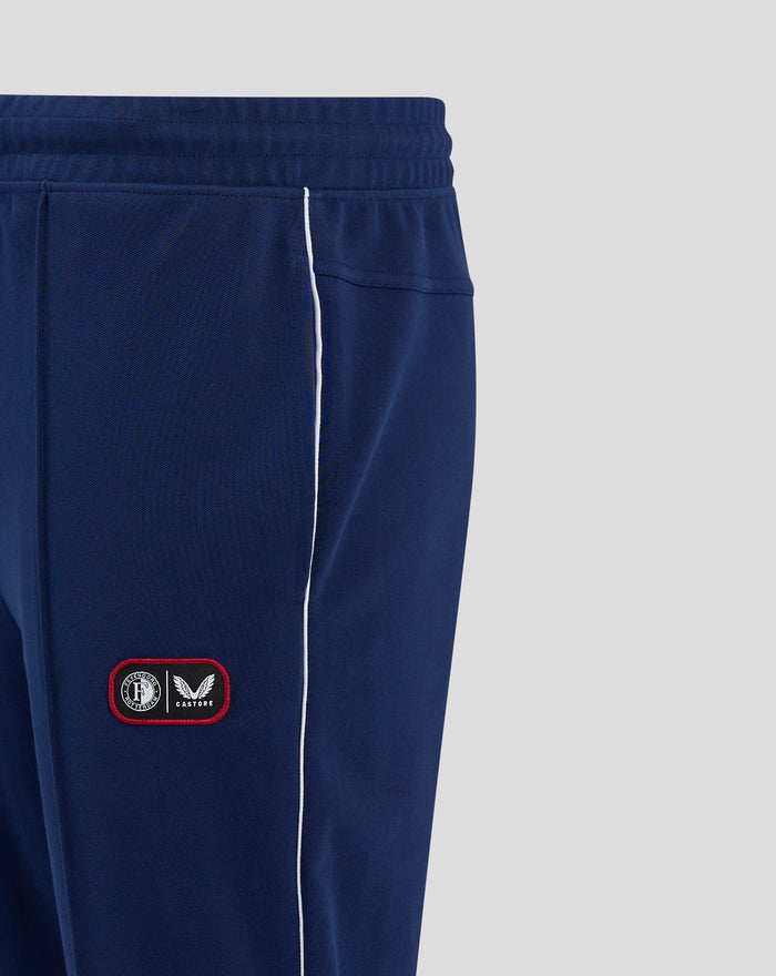 Close up of navy training pants leg with white piping and badge featuring Feyenoord crest and Castore logo