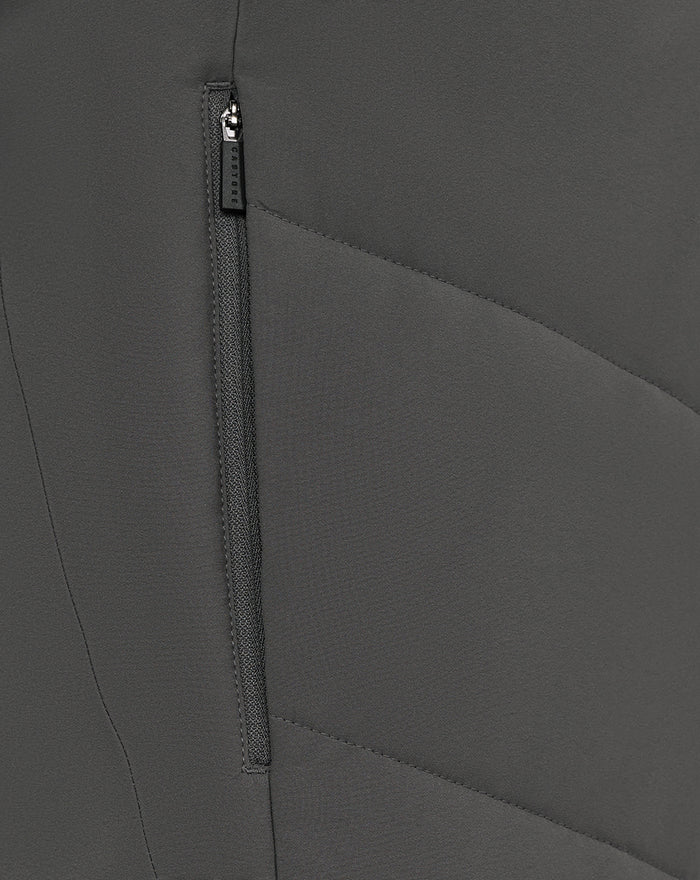 Close-up of a dark grey training jacket showing a vertical zipper and seam details with Castore pull