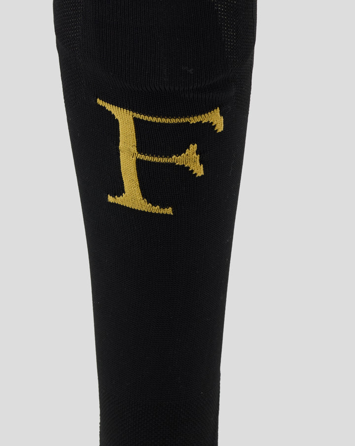 Close-up of a black Feyenoord home sock with a gold Castore logo on the calf