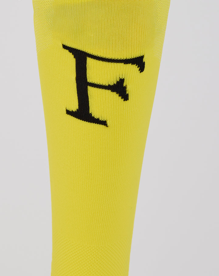 Close up of a large black logo on the yellow Feyenoord home goalkeeper sock