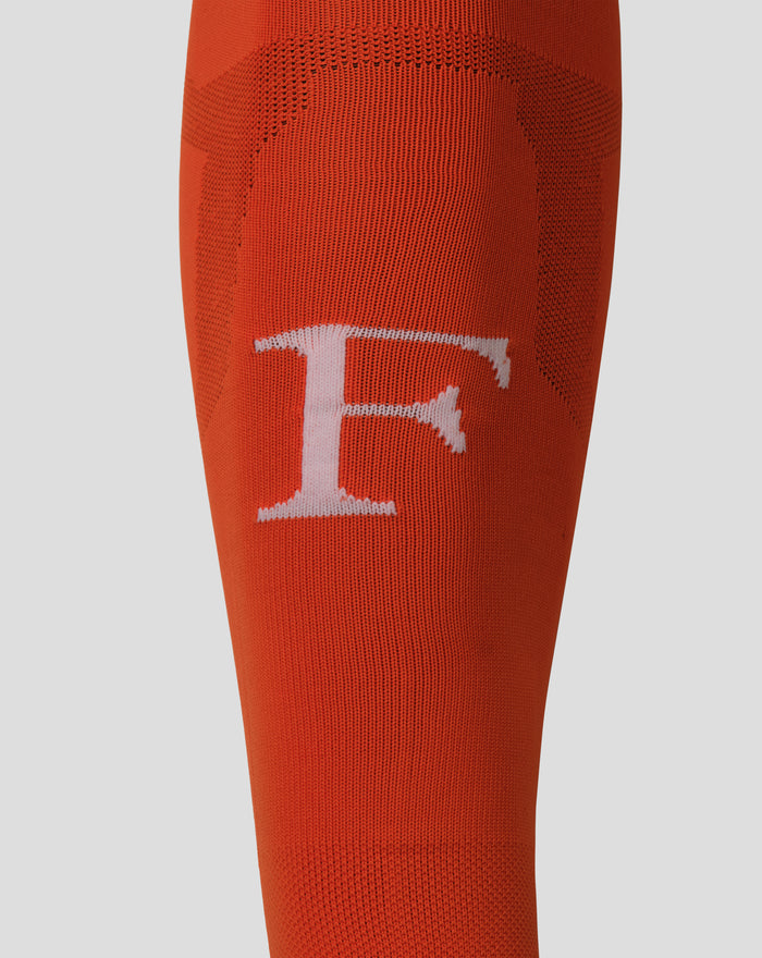 Close up of orange Feyenoord keeper sock showing knit texture and a white emblem on the lower leg