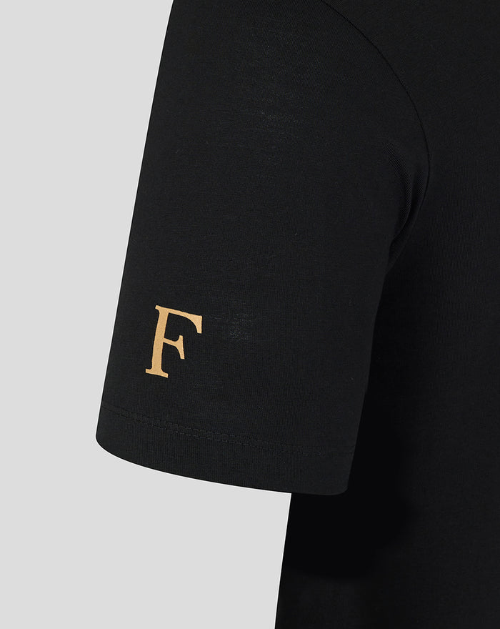 Close-up of a black T-shirt sleeve with a gold F emblem near the hem
